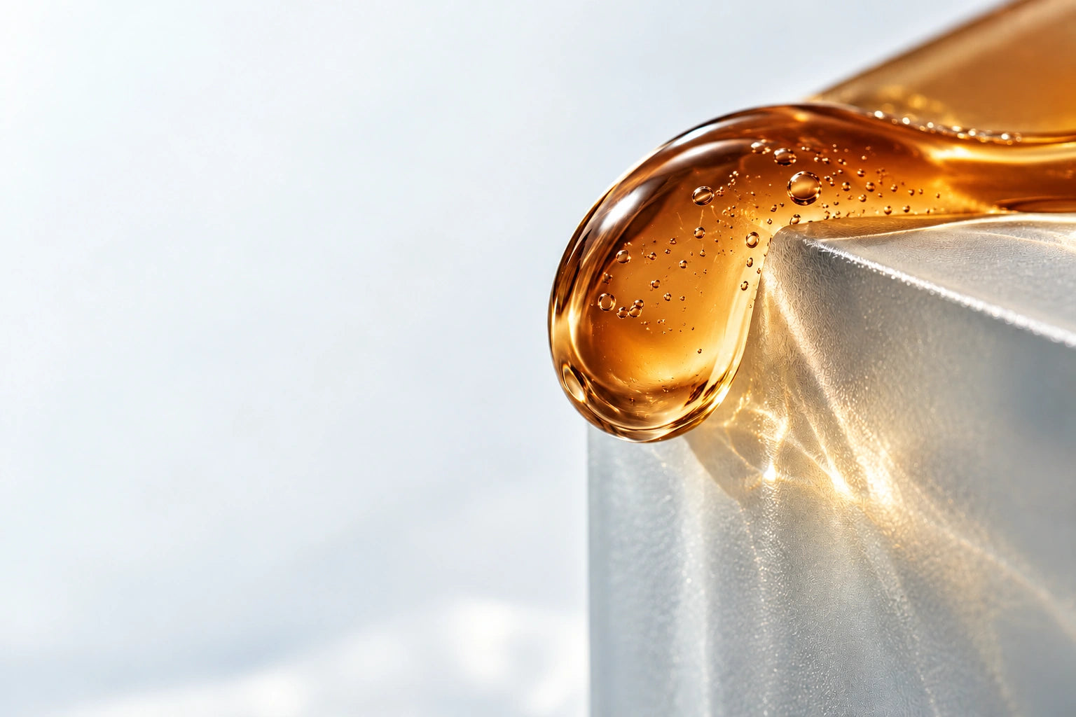 Luce e una goccia ambrata su vetro satinato